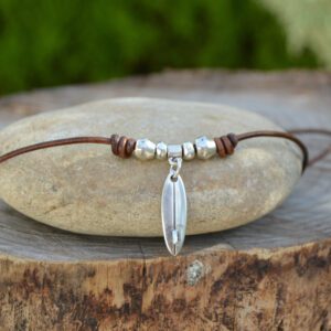 Silver plated metal surfboard necklace with adjustable leather cord and sliding knot.