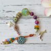 Bracelet with mix of colorful glass beads and, dolphin, fish and blanket fish pendants and clasp with button and leather.