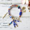 Pulsera ecléctica de mezcla de cuentas de vidrio reciclado en azul, blanco y rojo con colgantes pluma, runa y mariposa y cierre de palo