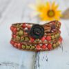 Bracelet enroulé en trois tours avec des perles de jaspe rouge, des perles en laiton et un fermoir en forme de fleur de rose noire.