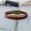 Leather strip bracelet in red with bronze beads and magnet fastener