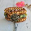 Wide bracelet in green and earth tones with floral metal button.