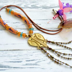 Necklace with golden African pendant finished with leather bangs, orange and blue recycled glass beads