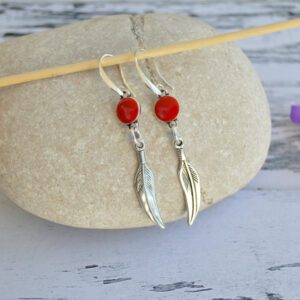 Longues boucles d'oreilles avec crochet hippie, pendentif plume et connecteur avec perles en résine rouge avec crochet hippie, le tout en zamak argenté.