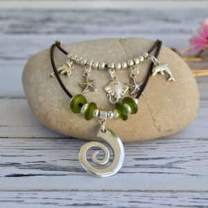 Leather choker with two layered strands with marine charms: stingray fish, two starfish, two dolphins, a spiral and green recycled glass beads.