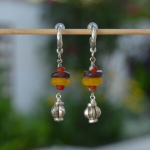 Pendientes de zamak plateado con cuentas de cristal reciclado africano en tonos cálidos y cuentas pequeñas de cristal checo y cierre aro con botón de silicona